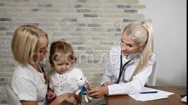 儿童健康检查。 年轻的母亲和她漂亮的小女儿去看家庭医生。 友好的儿科医生